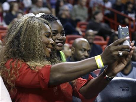 Tennis player Serena Williams, left, poses for a photo with a fan during an NBA basketball game between the Miami Heat and Utah Jazz, Monday, Dec. 16, 2013, in Miami. The Heat defeated the Jazz 117-94. (AP Photo/Lynne Sladky