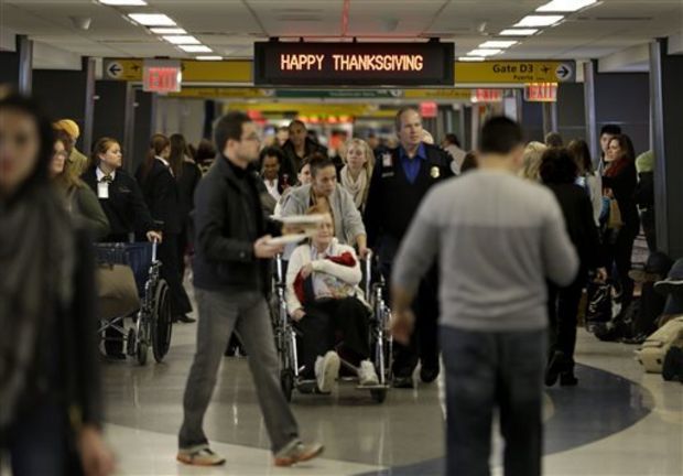 In this Nov. 26, 2013 file photo, travelers walk under a sign reading "Happy Thanksgiving" at LaGuardia Airport in New York. There will be 12.3 million roundtrip passengers, globally, on U.S. airlines during the 2014 holiday travel period, up 1.5 percent from 2013, according to the industry's lobbying group, Airlines for America. (AP Photo/Seth Wenig, File)
