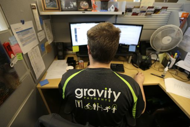 Austin Roos, a support team supervisor, works at his desk Wednesday, April 15, 2015, at Gravity Payments, a credit card payment processor based in Seattle. Gravity CEO Dan Price told his employees this week that he was cutting his roughly $1 million salary and using company profits so they would each earn a base salary of $70,000, to be phased in over three years. (AP)