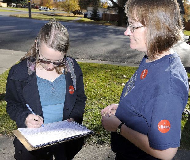 In this Nov. 6, 2012 photo, Chelsea Corbridge, left, signs a petition for Rebecca Saldivar, trying to get the issue of alcohol sales in Hyde Park, Utah onto the ballot. Residents can vote to lift a long-standing ban on the sale of alcohol in Tuesday’s election. Hyde Park, population 4,000, is among a handful of dry cities left in a state known for its tee totaling ways. (AP Photo/The Herald Journal, Eli Lucero)