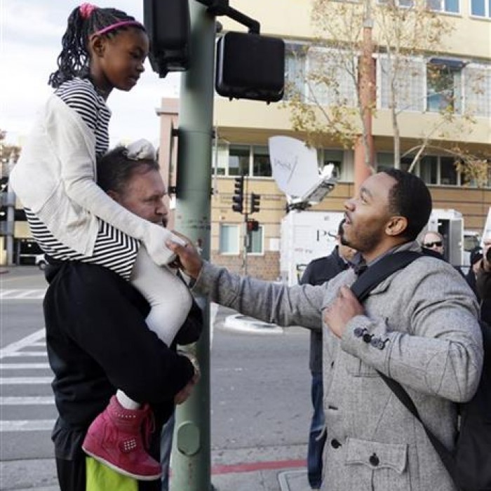 Omari Sealey, at right, shakes hands with well-wishers Frank Somerville, at left, and his daughter Callie, 9, after Sealy made a statement for the media on the condition of his niece Jahi McMath on Monday, Dec. 30, 2013, in Oakland, Calif. (AP Photo/Marcio Jose Sanchez)