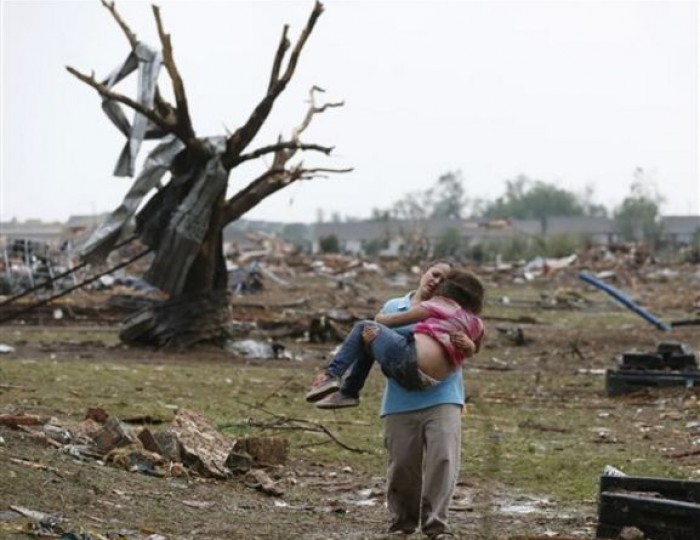 LaTisha Garcia carries her 8-year-old daughter, Jazmin Rodriguez, near Plaza Towers Elementary School, May 20, 2013, after a massive tornado carved its way through Moore, Okla., leaving little of the school and neighborhood. This image was chosen by the Associated Press as one of the top 10 news photos representing the top stories of 2013. (AP Photo/Sue Ogrocki, File)