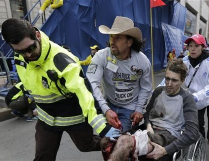 An emergency responder and volunteers, including Carlos Arredondo in the cowboy hat, push Jeff Bauman in a wheel chair after he was injured in an explosion near the finish line of the Boston Marathon Monday, April 15, 2013 in Boston. This image was chosen by the Associated Press as one of the top 10 news photos representing the top stories of 2013. (AP Photo/Charles Krupa, File)