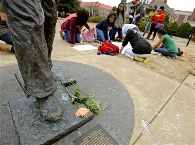 A flower rests at the foot of the James Meredith statue as students make signs during protest at the University of Mississippi in Oxford, Miss., Tuesday, Feb. 18, 2014. (AP Photo/The Daily Mississippian, Thomas Graning)