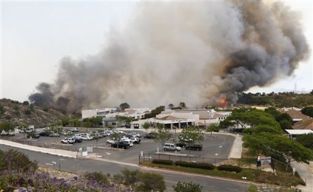  wild fire burns toward a Aviara Oaks Middle School Wednesday, May 14, 2014, in Carlsbad, Calif. Wind-driven flames are threatening homes in the coastal city of Carlsbad, where officials have sent mandatory evacuation notices to more than 11,000 homes and businesses. (AP Photo)