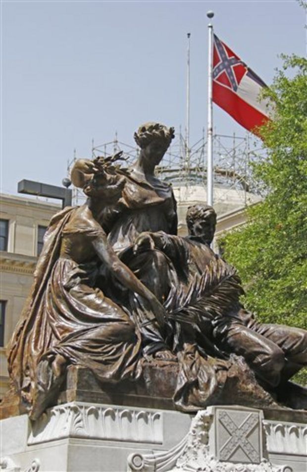 A statue erected in memory of the mothers sisters, wives and daughters of the Confederate soldiers sits before the state Capitol in Jackson, Miss., Tuesday, June 23, 2015, as the state flag flies behind it. Republican Lt. Gov. Tate Reeves said Tuesday, that Mississippi voters, not lawmakers, should decide whether to remove the Confederate battle emblem from the state flag. Reeves, who presides over the state Senate, spoke about the issue a day after Republican House Speaker Philip Gunn called the emblem offensive and said the state flag should change. (AP Photo/Rogelio V. Solis)