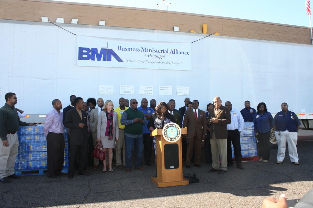 The coalition of city officials, business and religious leaders stand in front of two trucks loaded with water for South Carolina flood victims