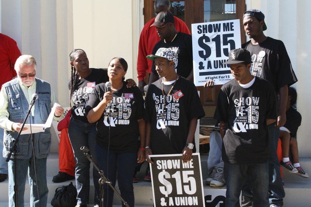 Bill Chandler, (from left), Cajania Brown, Kenyata McInnis, and other fast-food workers stand on the steps of City Hall in Jackson Tuesday as they rally for an increase in minimum wage. Photo by Shanderia K. Posey