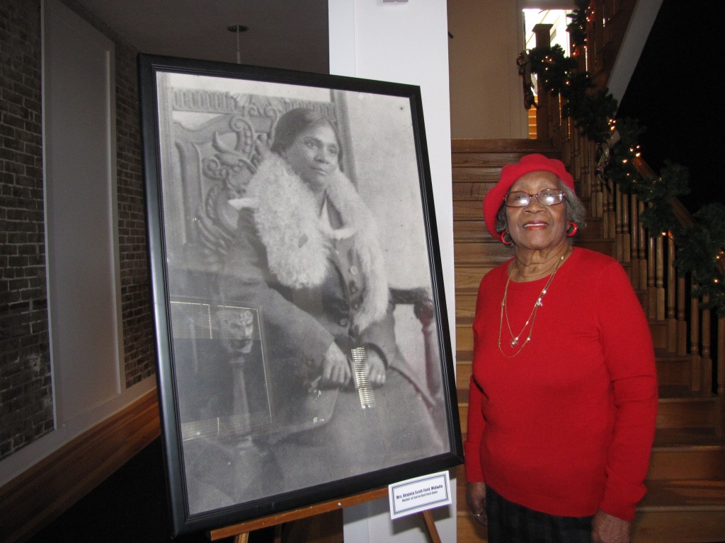 Ruth Weir stands next to a photo of her grandmother, Virginia Scott Ford, who was a midwife. PHOTOS BY JANICE K. NEAL-VINCENT
