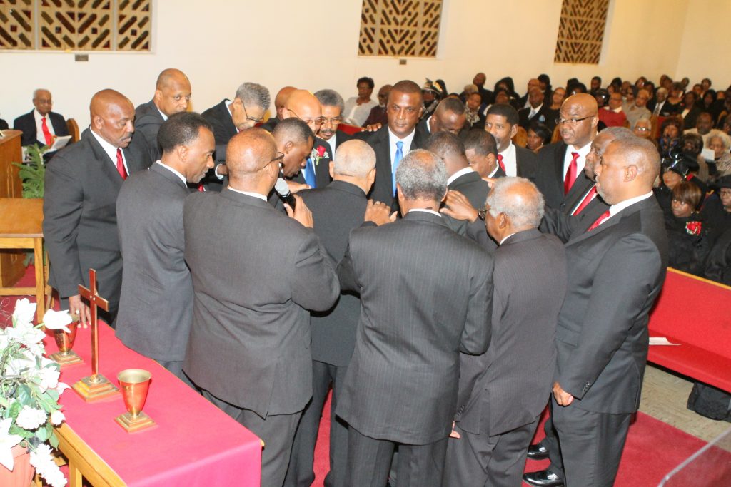 Current deacons and ministers laying hands on new deacons during ordination charge