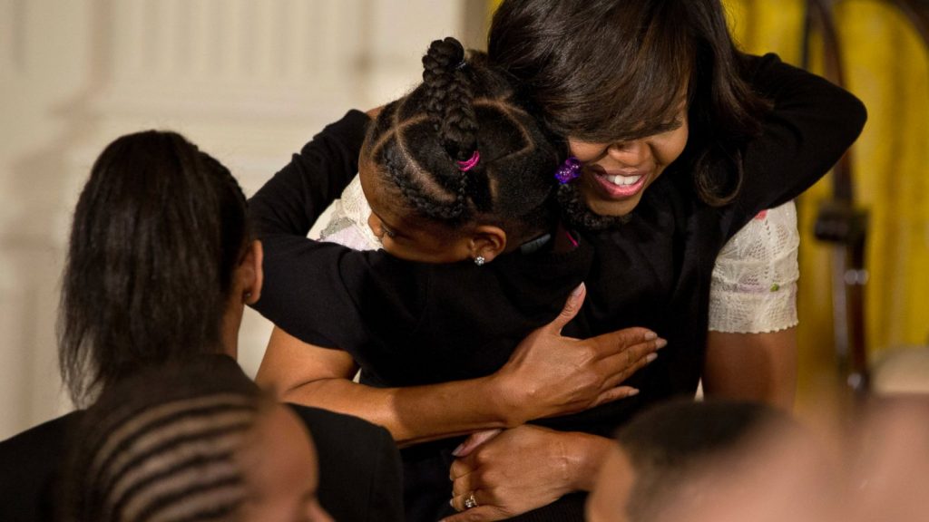 This April 20, 2016 file photo shows First Lady Michelle Obama giving a hug to a child during the annual White House Take Our Daughters and Sons to Work Day event attended by the children of Executive Office employees, young people from Big Brothers Big Sisters of America, SchoolTalk, and the D.C. Child and Family Services Agency, in the East Room of the White House in Washington. The feel-good initiatives of First Lady Michelle Obama have served as both inspiration and eight years of teaching moments for many families. AP Photo/Jacquelyn Martin