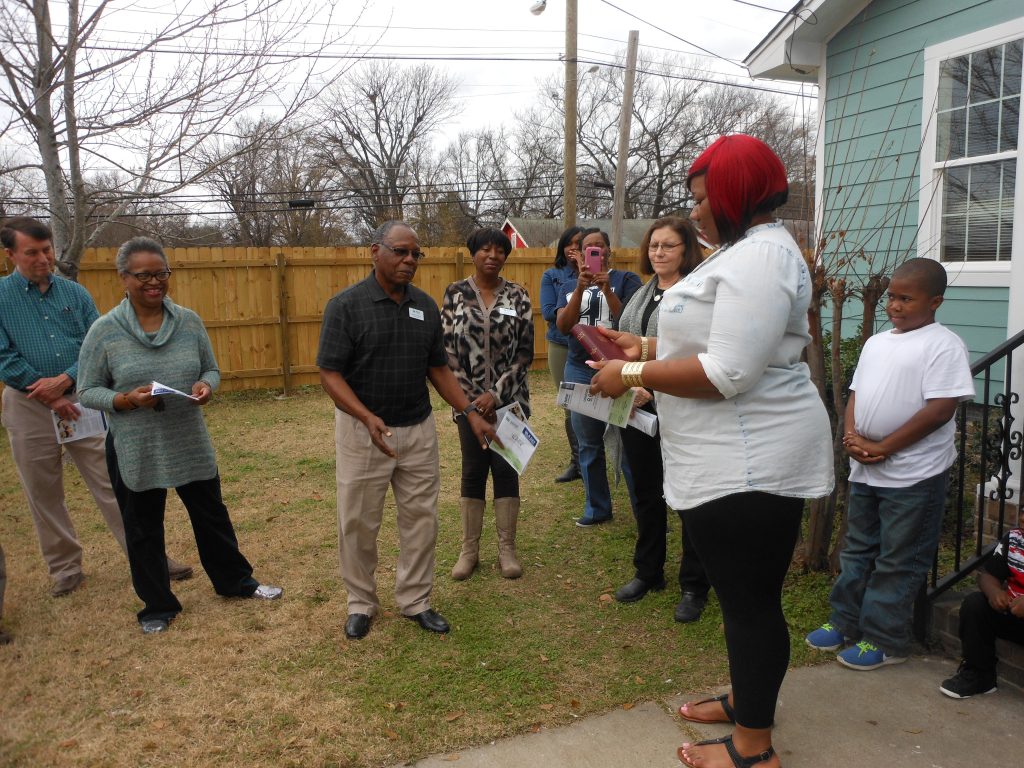 Habitat for Humanity board member Johnny Anthony presents a Bible to new homeowner Tierra Christian on Kevin Garnett St.