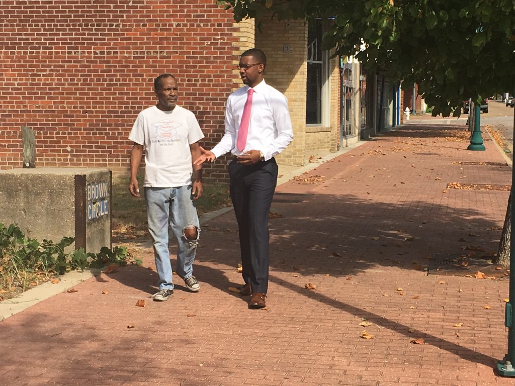 Business owner T. Dennis walks Farrish Street with LaDarion Ammons.