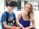 Jenifer Miehlbradt helps a 6-year-old child try virtual-reality games for the study, which found that head-torso coordination develops more slowly than previously thought. (EPFL/Alain Herzog)